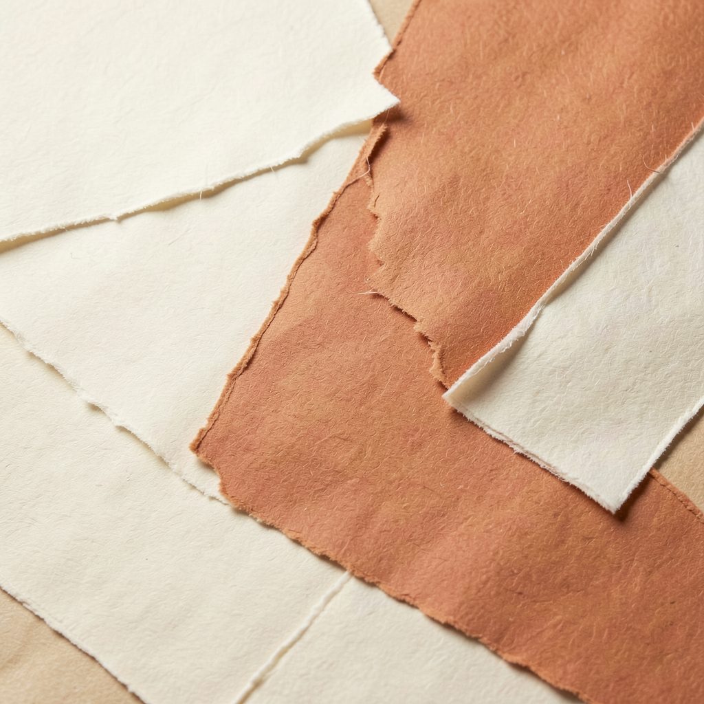 Composition abstraite de papiers texturés aux tons crème, beige et terracotta, superposés avec délicatesse dans une ambiance douce